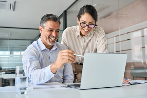 Two individuals focused on a laptop screen, engrossed in their work.