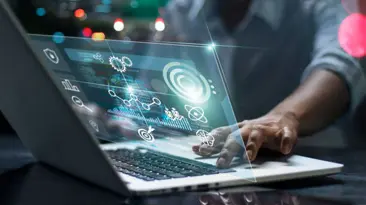 A person typing on a laptop with a digital interface, focused and engaged in their work.