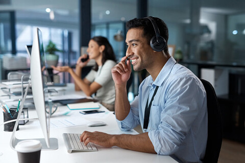 A professional man wearing headphones while working in an office.