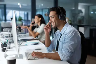 A professional man wearing headphones while working in an office.