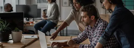 Un gruppo di persone in un ambiente d'ufficio che lavorano insieme e visualizzano lo schermo di un laptop