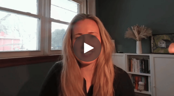 A blonde-haired woman sits in her room, speaking into her laptop - Video Cover Image