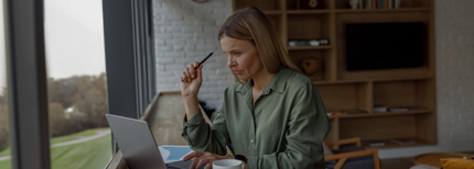 Uma mulher de negcios trabalhando no laptop no escritrio aconchegante enquanto est sentada perto de janelas