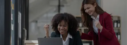 Two women looking at a computer in a corporate workplace