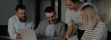 a group of people in an office looking at a laptop