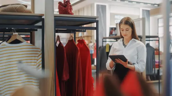 Une femme debout tenant un iPad dans un magasin de vtements