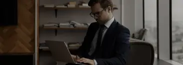 Un hombre sentado en su escritorio, escribiendo en su computadora porttil con una expresin concentrada