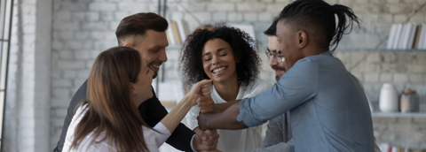 A team of professionals smiling as they join hands in the center