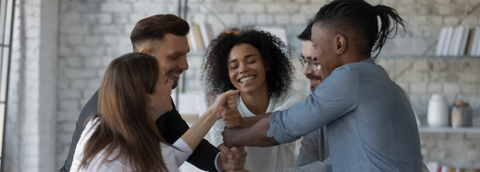 A team of professionals smiling as they join hands in the center