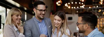 Four professionals in a casual, non-work setting, smiling and laughing together
