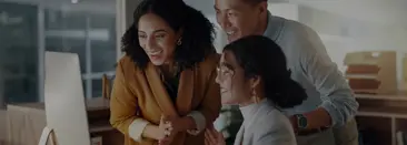 Trois professionnels souriants et regardant un cran d?ordinateur