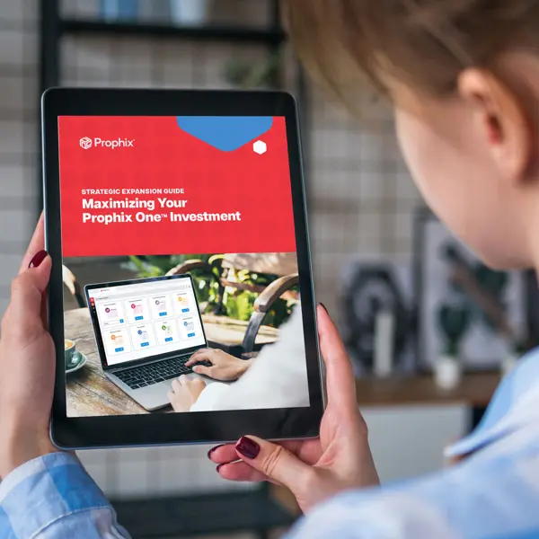 Een persoon die een iPad vasthoudt met tekst en een laptopscherm erop