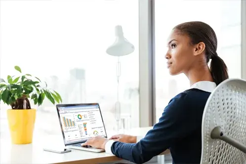 A woman seated and working on her laptop, momentarily looking away with a thoughtful expression as she tries to think