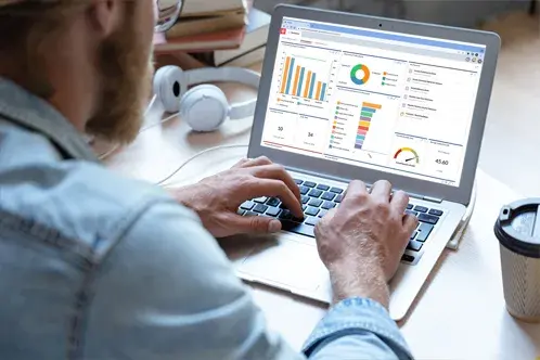 Un homme assis un bureau, tapant sur son ordinateur portable
