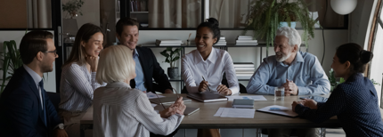 A team of employees and professionals sitting around a large desk at work