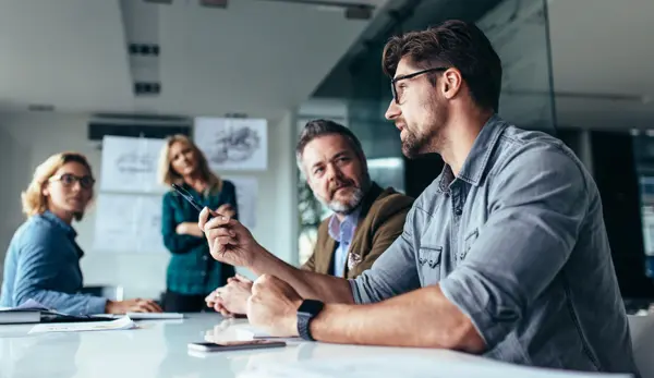 A diverse team of professionals engaged in a meeting around a table in a well-lit office space