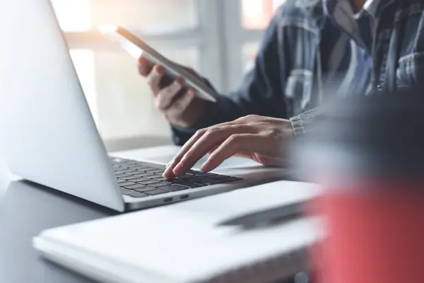 A person typing on a laptop computer, focused and engaged in their work.