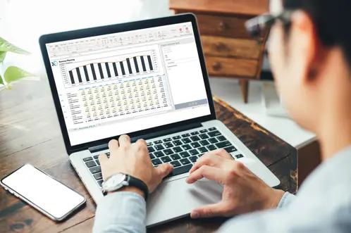 Een man die een laptop gebruikt met een staafdiagram dat op het scherm wordt weergegeven, gegevens analyseert en weloverwogen beslissingen neemt