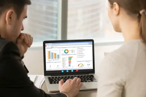Zwei Personen, die auf ihrem Laptop-Bildschirm auf ein Dashboard schauen