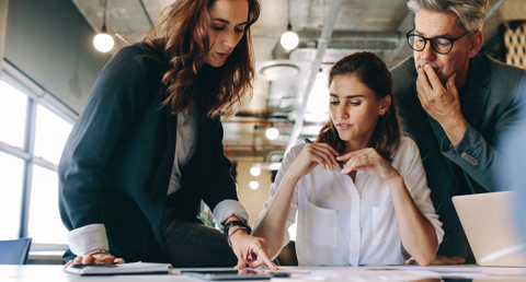 Tre professionisti che collaborano su un laptop, impegnati in una discussione produttiva.