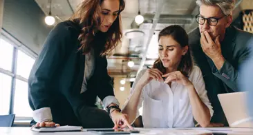 Drie professionals die samenwerken op een laptop, voeren een productieve discussie.