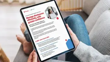 Eine Person in Jeans sitzt auf einer Couch und hlt ein iPad mit Text auf dem Bildschirm in der Hand