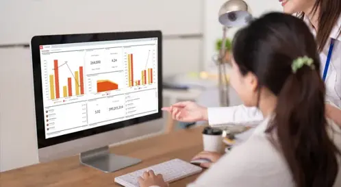 Two women examining a computer screen and analyzing a dashboard with graphs