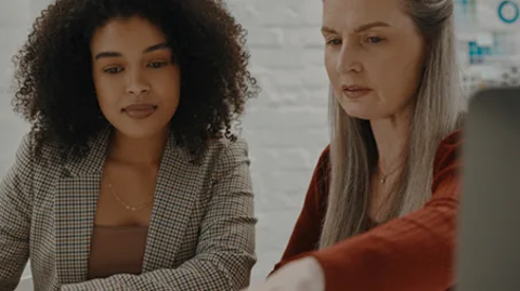 Two women reviewing documents together and deeply engaged in a serious professional discussion