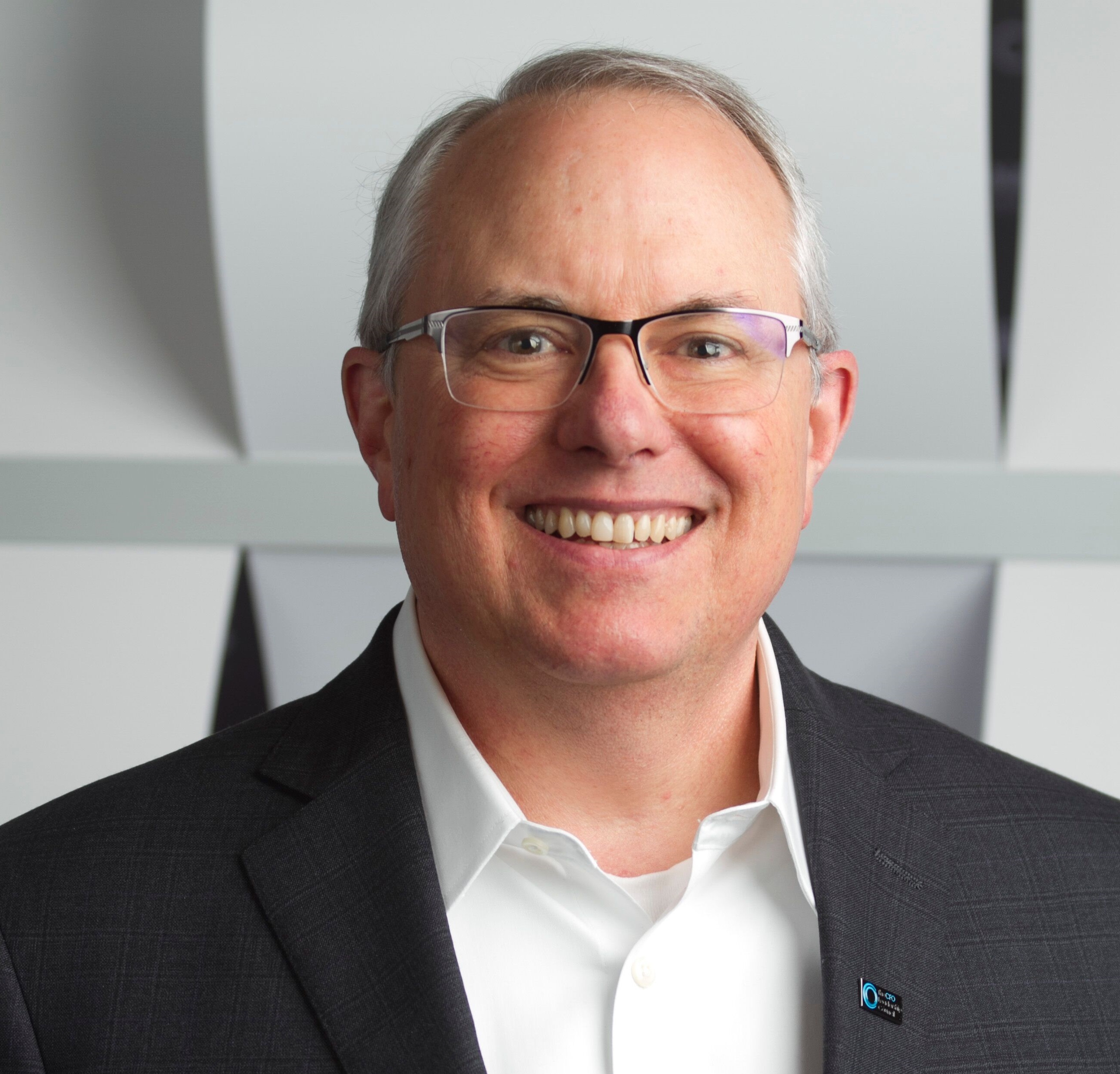 A man in a suit and glasses, smiling confidently