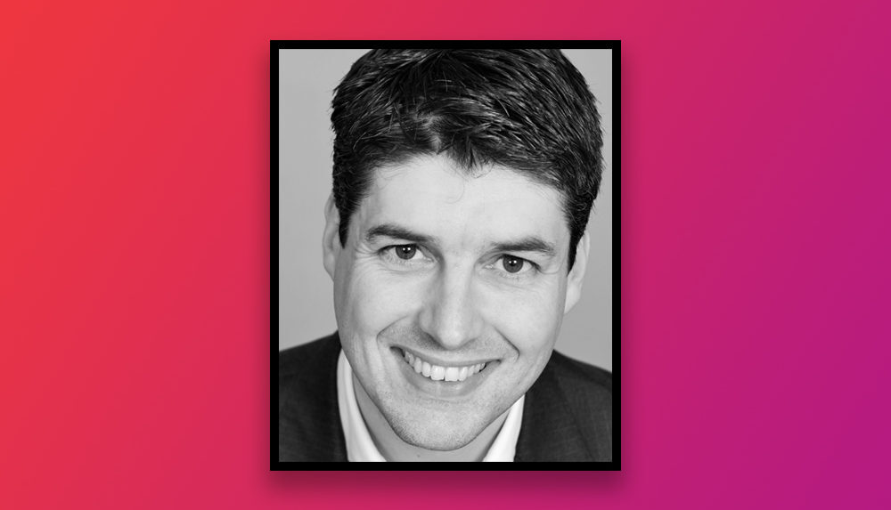 Black and white photo of a professional man smiling with visible teeth