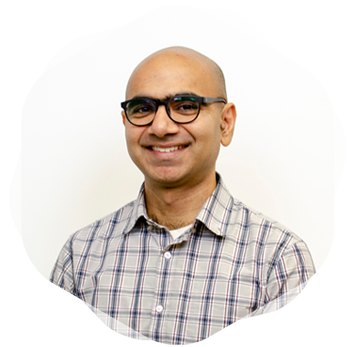 A man wearing black glasses standing and smiling