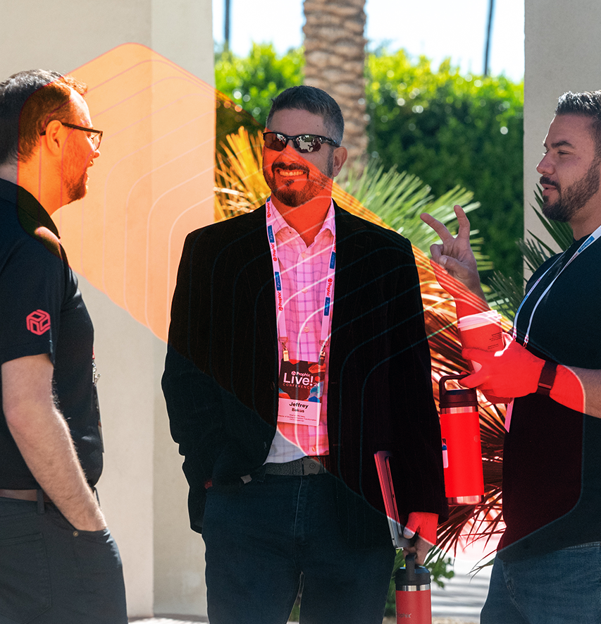 Three men standing together, smiling and engaged in conversation at the Prophix Live conference event