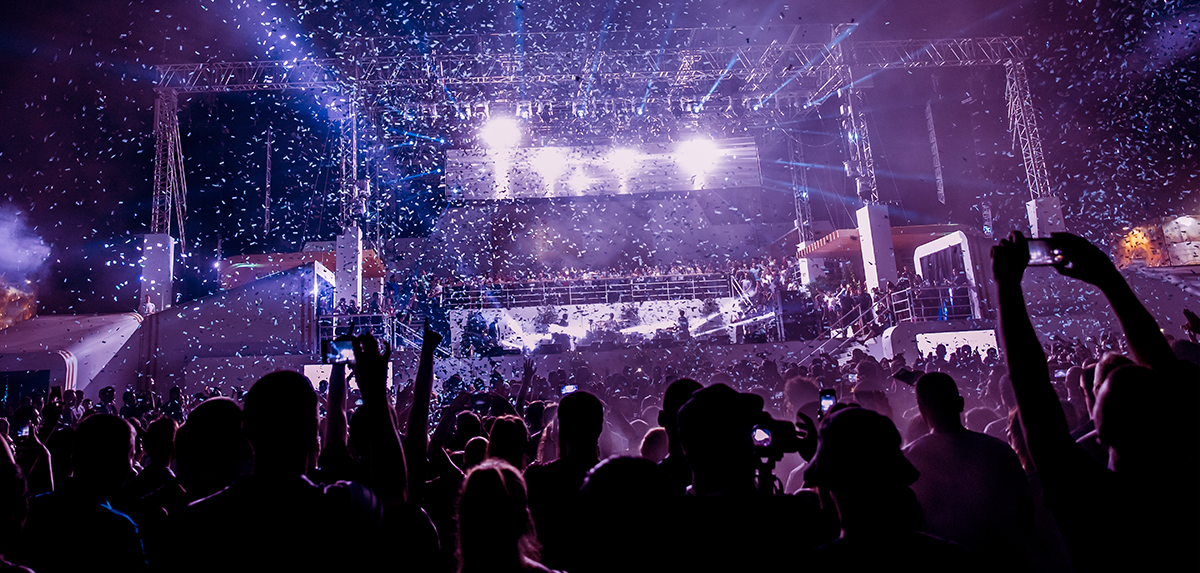 A lively concert crowd, with attendees raising their phones in excitement, capturing the moment