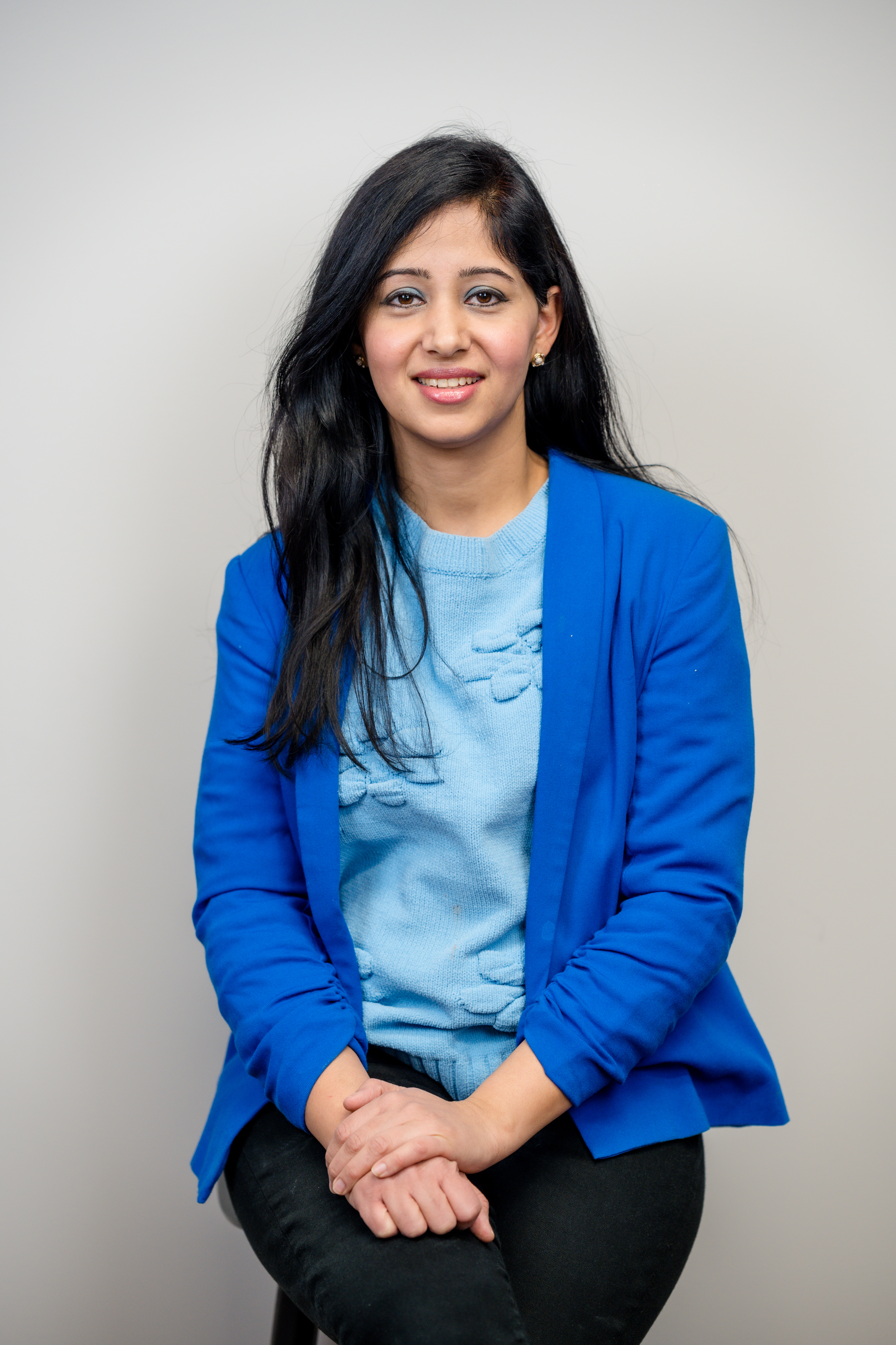 A woman in a blue blazer, seated and smiling pleasantly