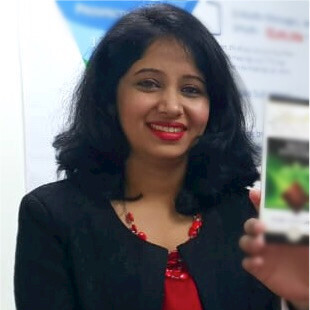 A woman wearing red lipstick and a red shirt, smiling while standing