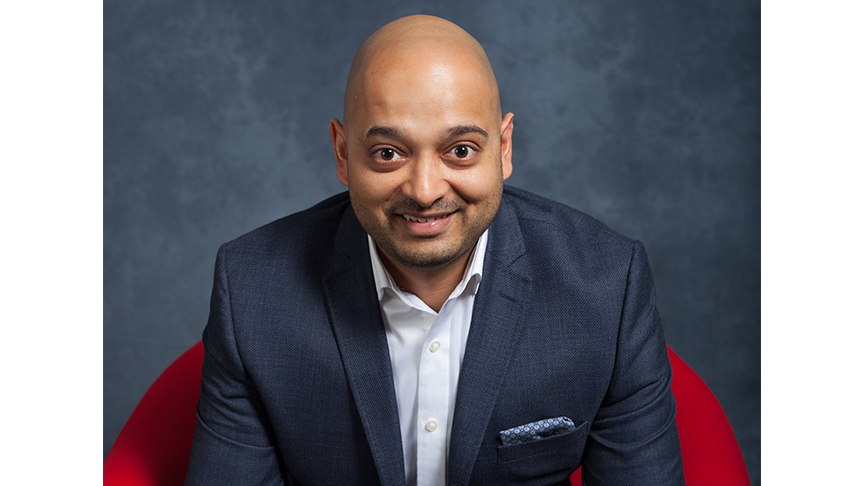 A professional man sitting on a red chair and smiling