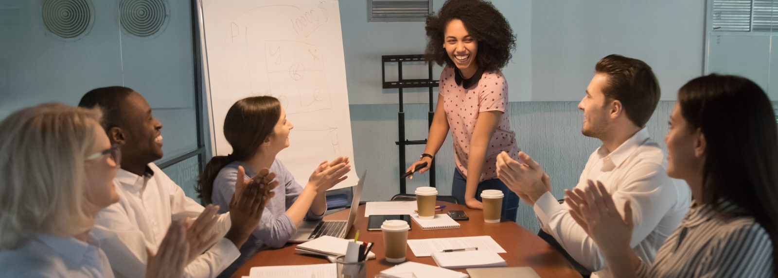 A woman confidently presenting to a group of attentive individuals during a professional meeting