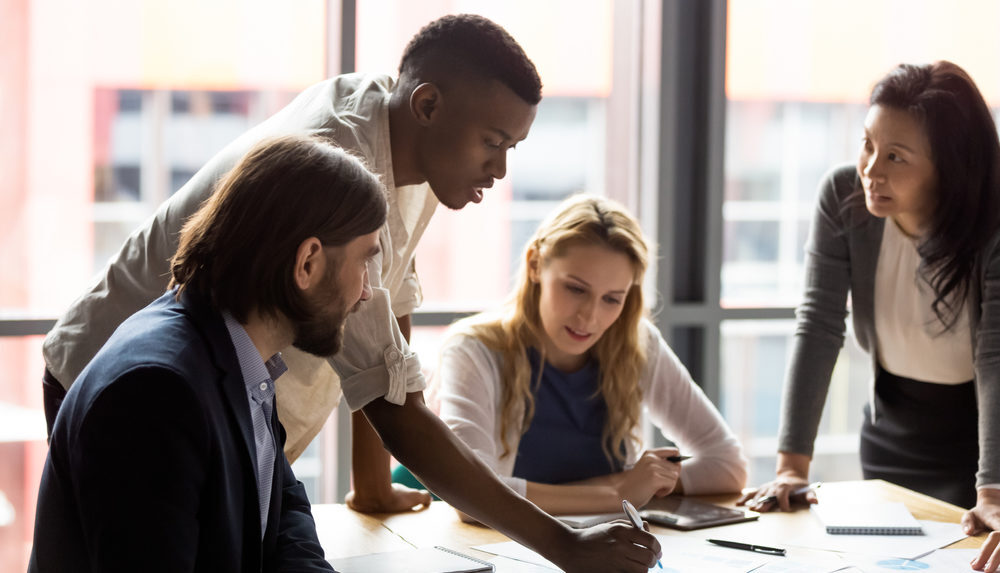 Un team diversificato che collabora in un ufficio moderno, lavorando insieme per raggiungere i loro obiettivi.