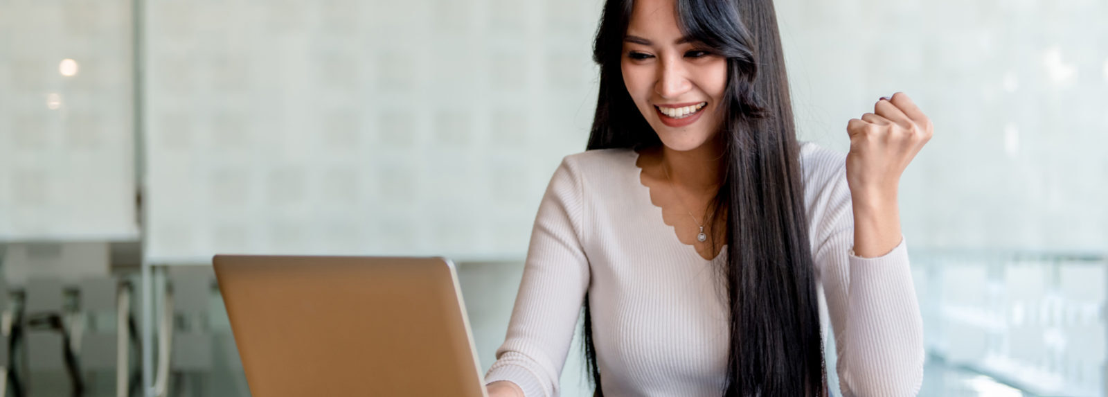 Una donna sorride mentre utilizza un laptop per svolgere i suoi compiti e comunicare con gli altri online.