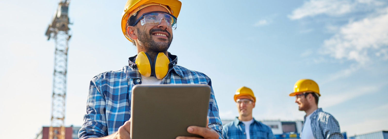 Un homme portant un casque et des lunettes de scurit tenant une tablette, prt  travailler sur un chantier de construction