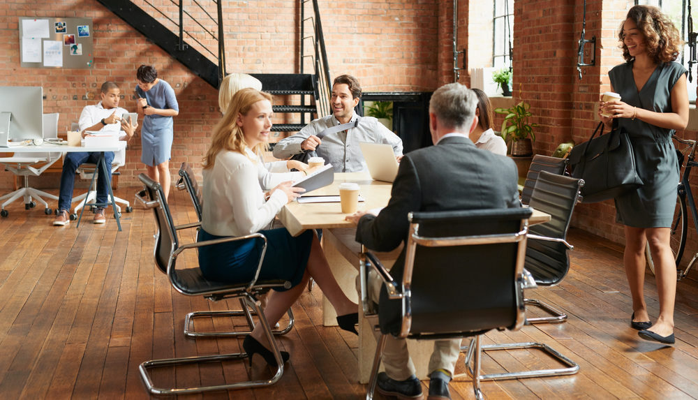 A diverse team of professionals engaged in a meeting, discussing ideas and collaborating at an office table