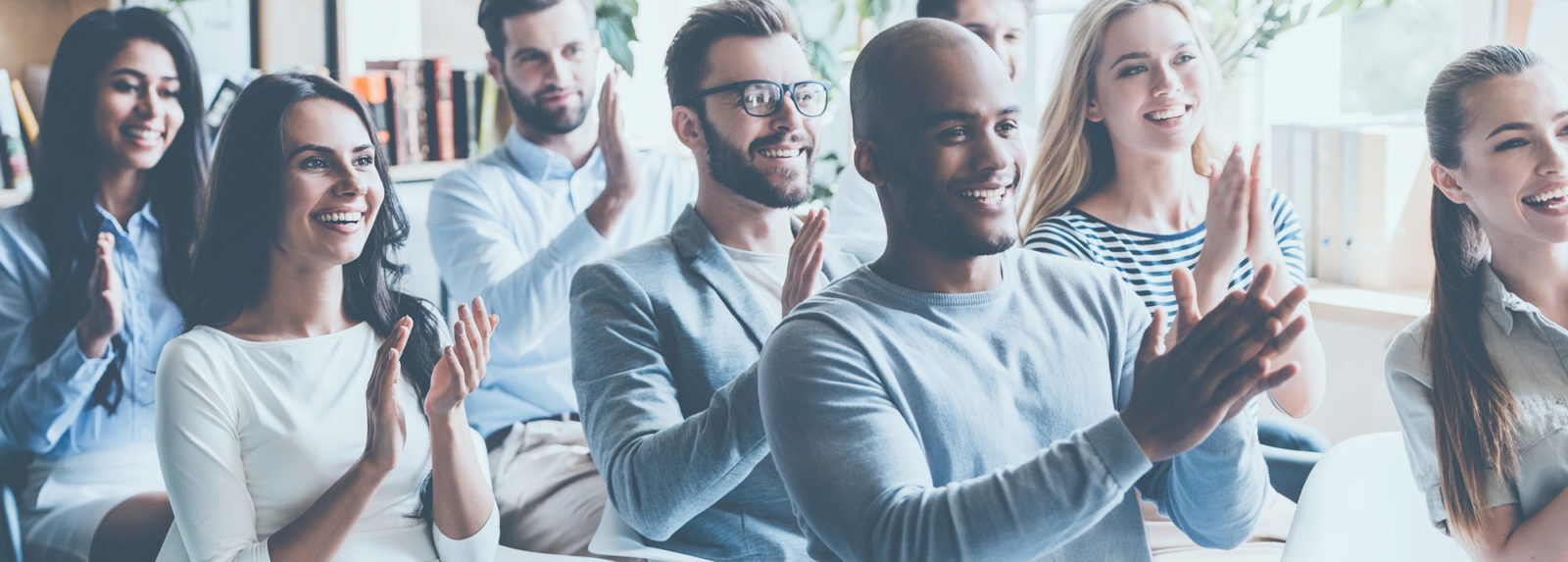 A group of people clapping in front of a screen, expressing their appreciation and enjoyment