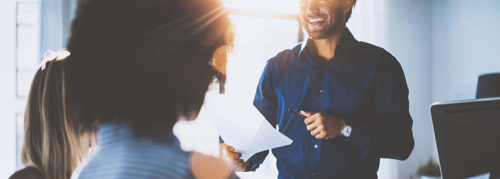 A man and a woman smiling and having a conversation in a professional office environment
