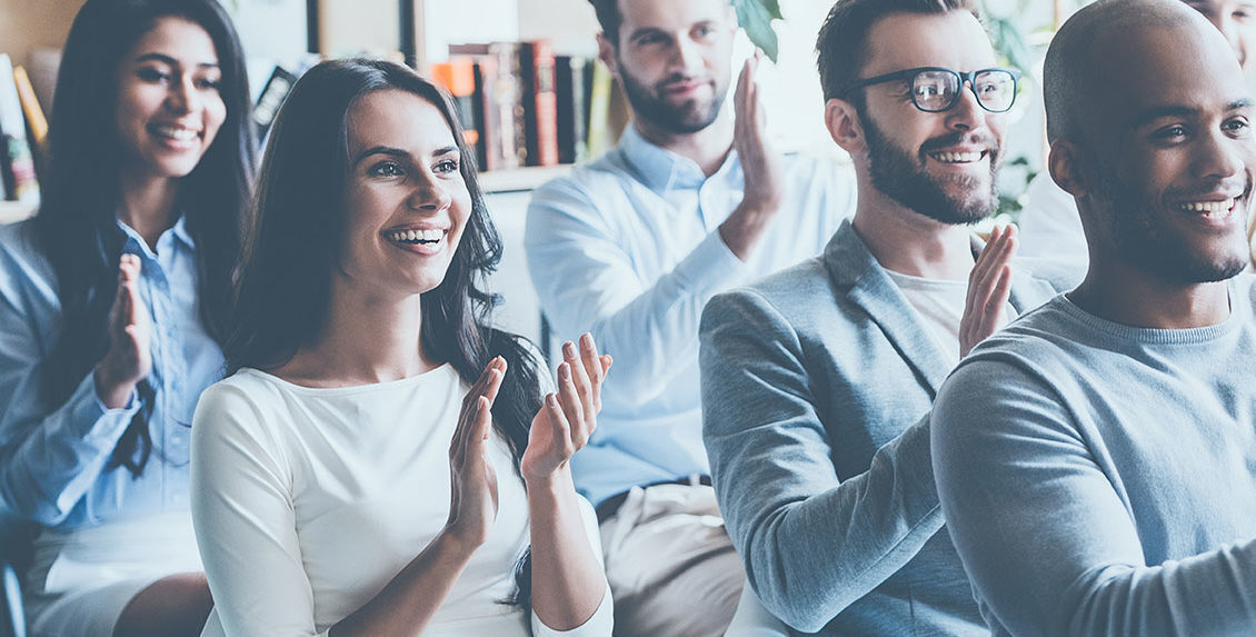 Un groupe de professionnels assis, souriant et applaudissant.