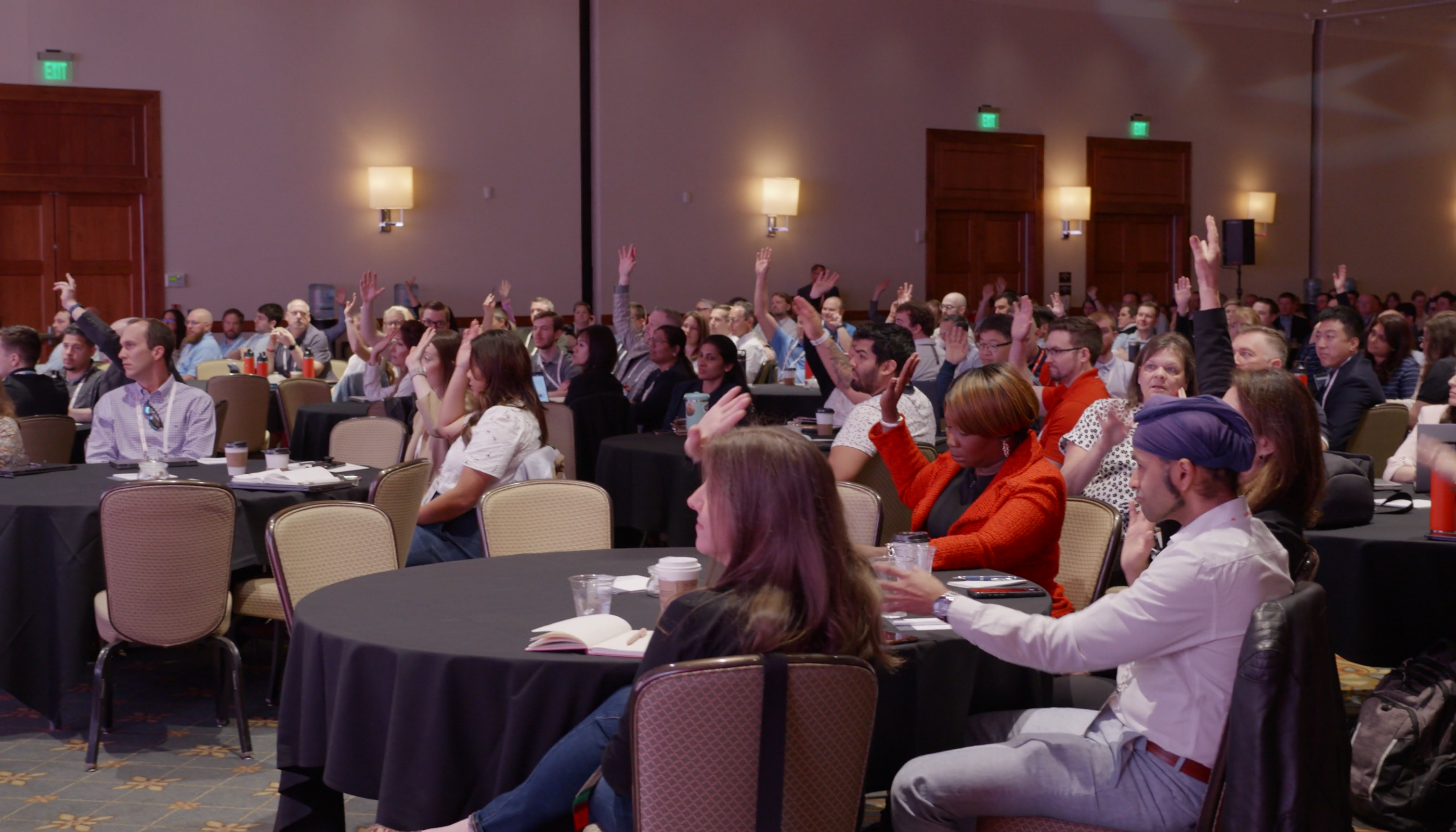 People raising their hands to ask questions during a Prophix Live event